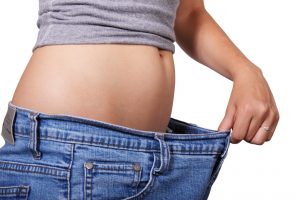 woman pulling jeans forward showing weight loss