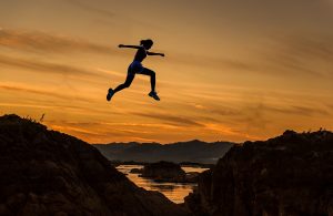 girl leaping between rocks